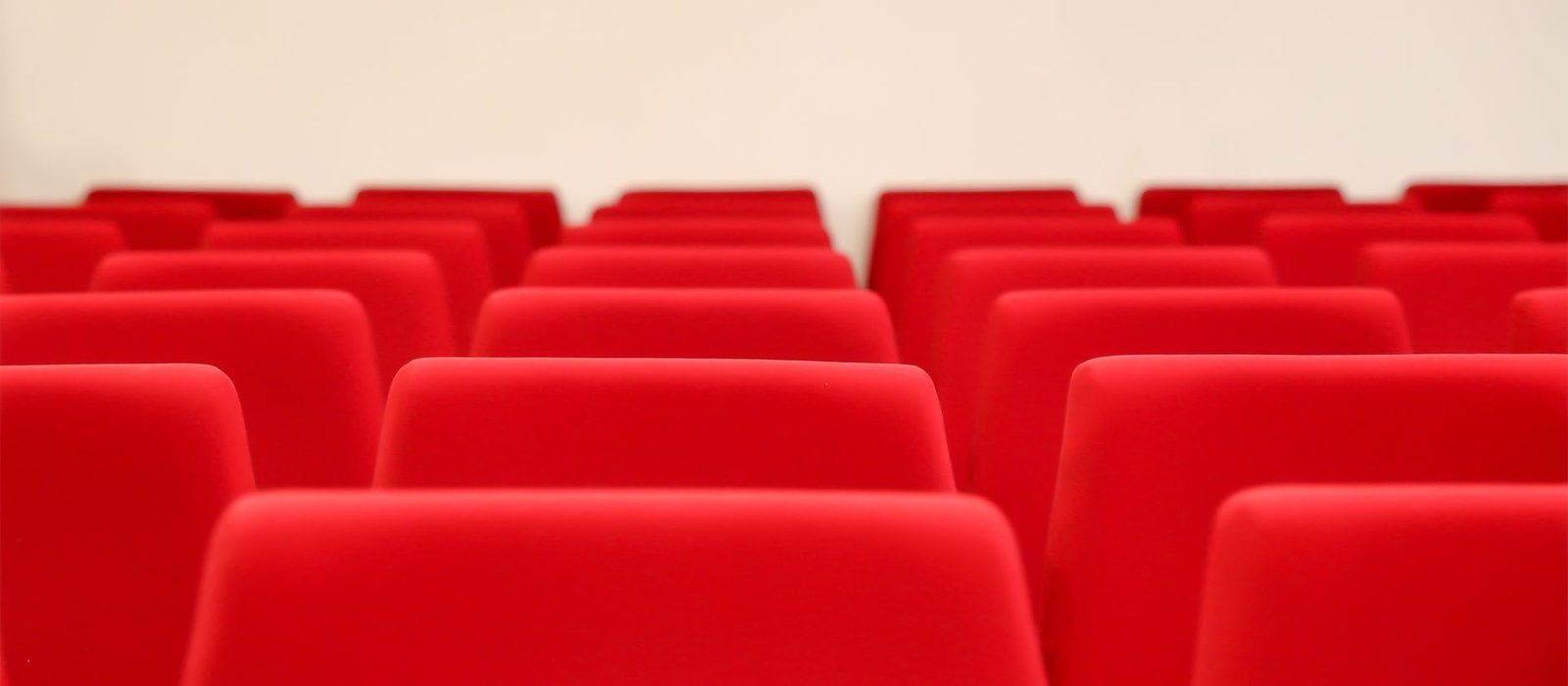 Rows of red auditorium seats in an empty venue before an event